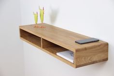 a wooden shelf that has two small birds on it and a cell phone sitting on top