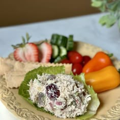 a plate filled with salad and fruit on top of a table