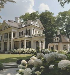 a large white house surrounded by trees and flowers