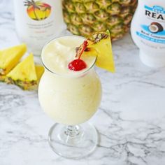 a glass filled with ice cream next to sliced pineapples