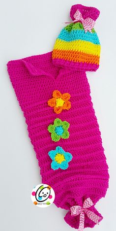 a pink crocheted bag with flowers on the side and a hat on top