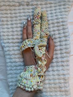 a woman's hand with crocheted gloves on top of a white blanket