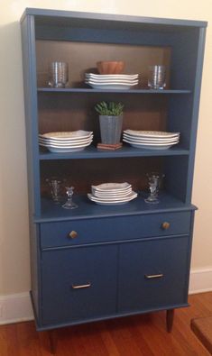 a blue china cabinet with plates and cups on it