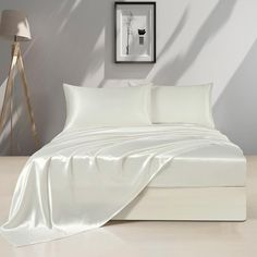 a bed with white sheets and pillows on top of it next to a floor lamp