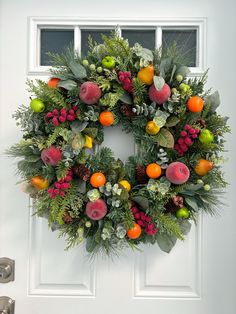 a wreath with fruit and greenery hanging on the front door to an apartment building