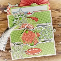 a close up of a card on a wooden surface with paper flowers and tassels