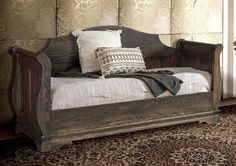 a wooden day bed sitting on top of a rug next to a potted plant