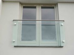 an open window on the side of a white building with glass balconies and metal bars