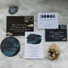 the wedding stationery is laid out on a furnishing area with rocks and paper