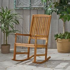 a wooden rocking chair sitting next to a potted plant