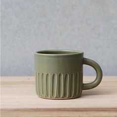 a green mug sitting on top of a wooden table