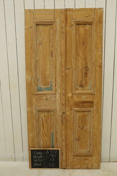 an old wooden door with a chalkboard on the front and bottom panel, against a white wall