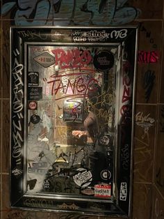 a bathroom with graffiti all over the walls and on the wall is a framed mirror