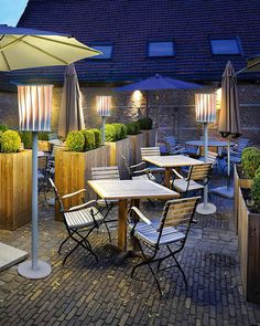 an outdoor dining area with tables and chairs, umbrellas and potted planters