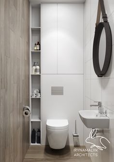 a white toilet sitting next to a sink in a bathroom under a mirror and hanging on the wall