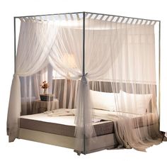 a canopy bed with sheer curtains over it and a night stand next to the bed