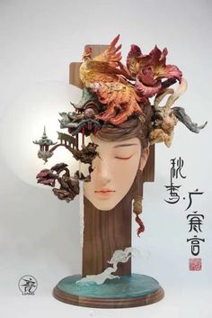 a sculpture of a woman's head with flowers and birds on top of it