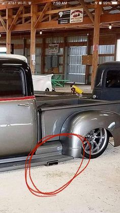 an old silver truck parked in a garage next to another black car with a red circle around it