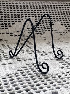 a black metal hook sitting on top of a bed