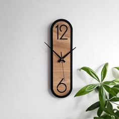 a wooden clock on the wall next to a potted plant