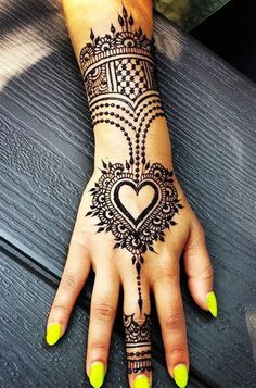 a woman's hand with a henna tattoo on it and yellow nail polish