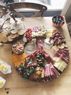 a wooden table topped with lots of different types of cheeses and crackers on top of it