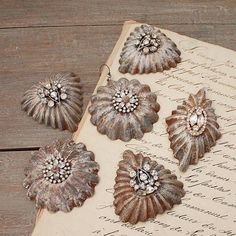 an old book with five antique flower brooches on it's cover, sitting on a wooden table