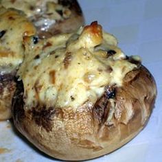 two stuffed mushrooms with cheese on them sitting on a white tablecloth covered counter top