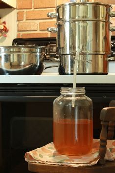 a glass jar filled with liquid sitting on top of a wooden table next to an oven