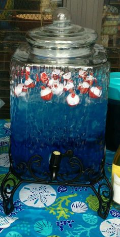 an ice chest with red and white candy in it on a blue table cloth next to bottles