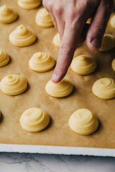 a person pointing at some yellow cookies on a cookie sheet