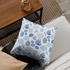 a blue and white pillow sitting on top of a couch next to a wooden table