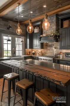 a kitchen with black cabinets and wooden counter tops, lights hanging from the ceiling over the island