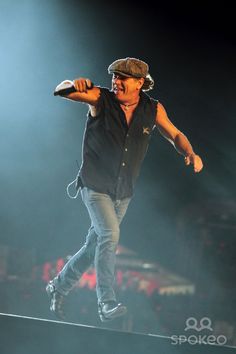 a man in black shirt and hat on stage with microphone