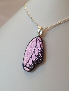 a pink and black leaf pendant on a silver chain