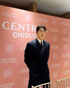 a man in a suit and tie standing next to a chair with the words central child on it