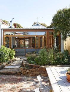 an outdoor patio area with tables, chairs and potted plants in front of the house