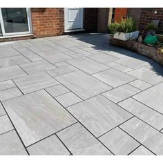 an outdoor patio with grey tiles on the ground and brick planters in the background