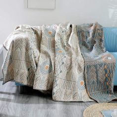 a couch with a blanket on top of it next to a chair and rugs