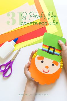 Child's hand holding a paper leprechaun with an orange beard and green top hat with a rainbow band, over a stack of colored paper, glue, and scissors. Rainbow With Pot Of Gold, Rainbow And Pot Of Gold, Leprechaun Rainbow, Do Crafts, Gold Decor