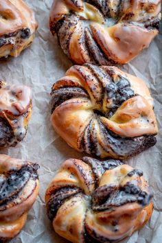 cinnamon buns with icing and powdered sugar sitting on top of wax paper