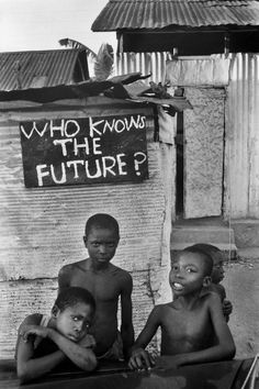 black and white photograph of three children in front of a sign that says who knows the future?