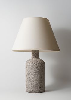 a table lamp with a white shade on it's base and an off - white background