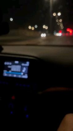 the dashboard of a car at night, with lights in the background and blurry image