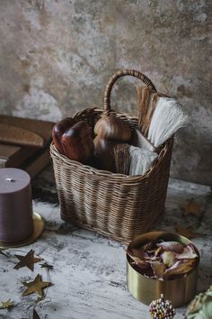 a wicker basket filled with different types of items next to a candle and other decorations