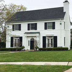 a large white house with black shutters on the front and side windows is shown