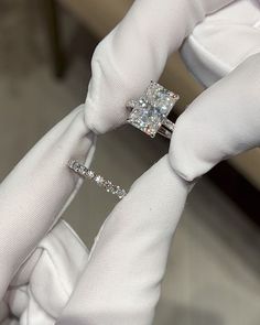 a pair of white gloves holding an engagement ring