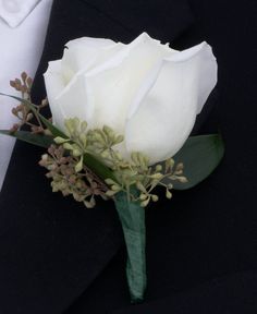 a boutonniere with white flowers and greenery on it's lapel