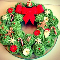 a green christmas wreath cake with red bows and candy canes on the top, sitting on a table