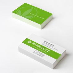 two business cards sitting on top of each other with green leaves in the middle and white bottom